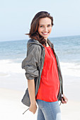 A young brunette woman wearing a red blouse, a grey windbreaker and jeans