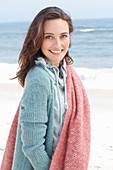 A young brunette woman wearing a hoodie, a cardigan and a woollen shawl