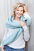 A blonde woman wearing a light knitted jumper and a woollen shawl