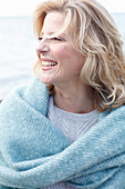 A blonde woman wearing a light knitted jumper and a woollen shawl