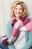 A blonde woman wearing a light jumper, a cardigan and a thick scarf