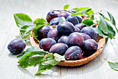 Plums with leaves in a bowl