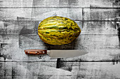 Santa Claus melon on a wooden background with a knife