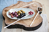 Verschiedene Oliven auf rustikalem Holzbrett