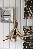 Lamp made from antlers and rope in front of white wall cladding
