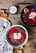 Bowl of Beetroot soup with coconut milk and sour cream, garnished with parsley and dill