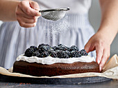 Dusting blackberry cake with powdered sugar