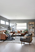 Leather sofas and armchair in cosy living room with grey walls
