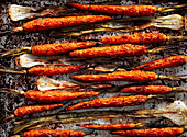 Geröstete Karotten und Schalotten auf Ofenblech (Aufsicht)