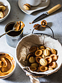 Walnut cookies in a basket with dulce de leche in a bowl and tea cup on gray background