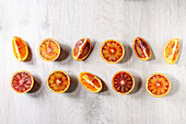 Group of fresh organic Sicilian blood oranges sliced and whole in row over white wooden background