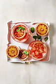 Blood orange iced cocktails in glasses, decorated by slice of oranges and fresh mint on skewers