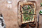 Asparagus tart on a brown board, with negative space