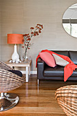 Designersessel, Beistelltisch mit Lampe und Glasvase und Ledersofa im Wohnzimmer