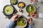 Family dinner. Variety of green vegetable soup asparagus, broccoli or pea, decorated by greens, cream, oil, in ceramic bowls