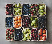 Summer fruit and berry variety: Flat-lay of strawberries, cherries, grapes, blueberries, pears, apricots, figs in wooden eco-friendly boxes