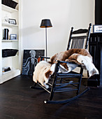 Painted Black rocking chair with animal hide throw in front of a shelf