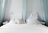 White double bed in bedroom with pale blue beams