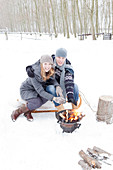 Couple warming hands on brazier in snowy landscape