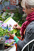 Frau beschriftet Karteikarten zur Gartenplanung