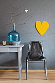 Vintage chair, branch in turquoise demijohn on desk and yellow heart on wall