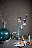 Branch in turquoise demijohn on desk against grey wall