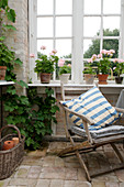 Old folding chair below lattice window with geraniums on the windowsill