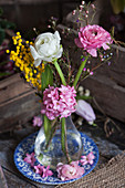 Ranunkel, Hyazinthe, Australische Wachsblume und Silber-Akazie in einer Glasvase