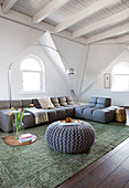 Sofa set in living room of attic apartment with white-painted wooden ceiling