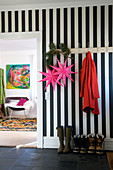 Black and white striped wall in a hallway, pink stars hanging from the hook coat rack