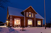 Illuminated brick house in the snow at dusk