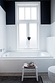 Bathtub below window in black-and-white bathroom