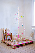 Minimalistic Christmas tree made of wooden sticks on a pallet covered with washi tape