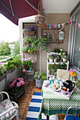 Üppig bepflanzter Balkon mit sommerlichen Blumen und Frühstückstablett
