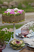 Floristik-Torte aus Nelken, Rosen und Beeren auf einem Tortenfuß