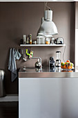 Küchentheke mit Edelstahl Arbeitsplatte, darüber Pendelleuchten in Küche mit brauner Wand