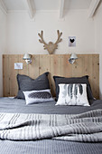 pillows with feather and pinecone graphics on a bed with a wooden headboard