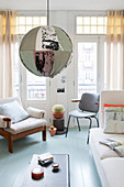 Kugelleuchte mit buntem Stoffschirm, helles Sofa, Stuhl und Sessel im Altbau-Wohnzimmer