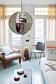 Colourful, spherical fabric lampshade, pale sofa, chair and armchair in living room of period apartment