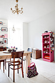 Solid wood table and pink shelving unit with dishes in the dining area