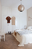 Doppelbett und weißer Einbauschrank im Schlafzimmer in Beigetönen