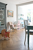 Dolls' pram in dining room with classic furniture and herringbone parquet floor