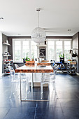 Transparent designer chairs around dining table in masculine kitchen-dining room