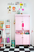 Colourful stickers on wall above pink cupboard and two sets of shelves