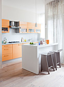 Yellow kitchen counter, white island counter and bar stool in open-plan kitchen