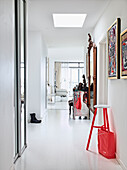 Red and white stool under works of art in the white hallway