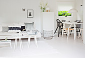 White couch with side tables and dining area with various chairs in a white, open living room