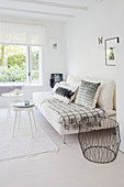 White couch with pillows, side tables and metal basket in a white living room