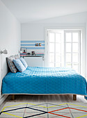 Blaue Tagesdecke auf dem Bett im schlichten Schlafzimmer