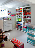Shelf with colorful fabrics and sewing accessories in the craft room